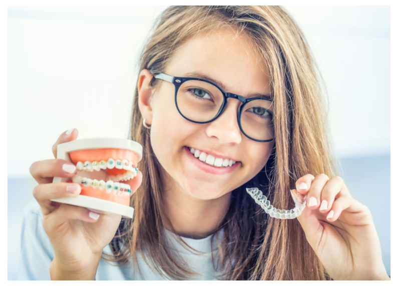 Young girl holding Invisalign and braces model smiling