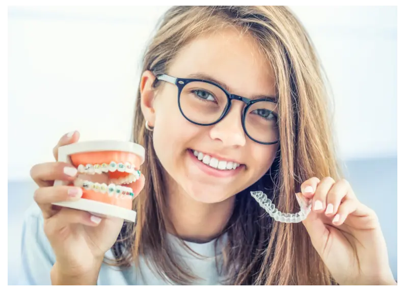 Joven sosteniendo un modelo de Invisalign y brackets sonriendo